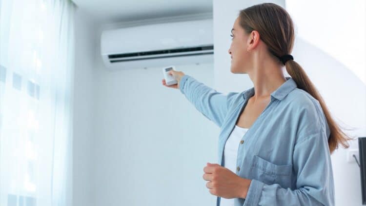Homeowner adjusting air conditioning unit to improve indoor air quality and airflow